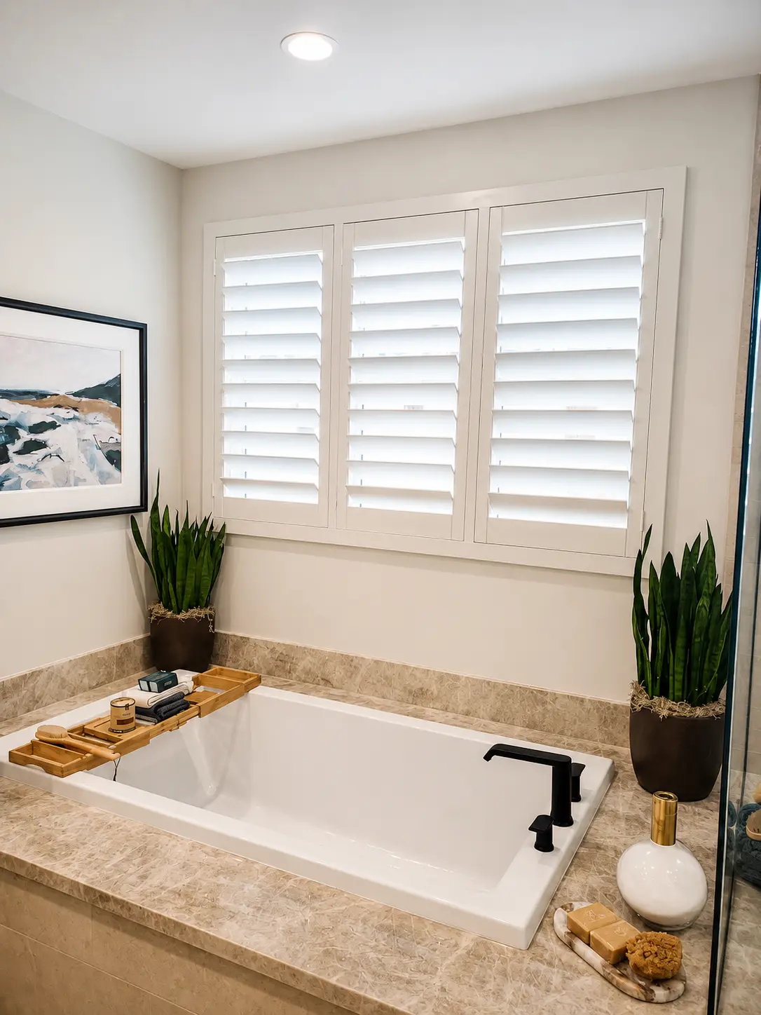 White plantation shutters above a soaking tub in a stone-tiled master bath
