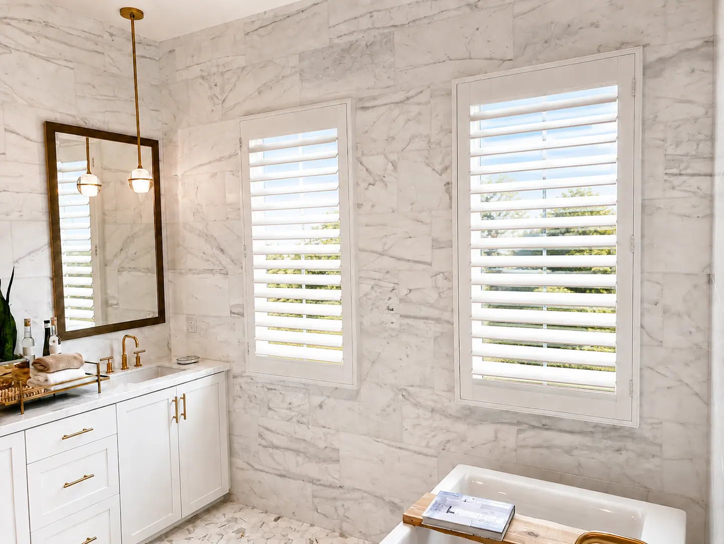 White plantation shutters in a marble-tiled master bath