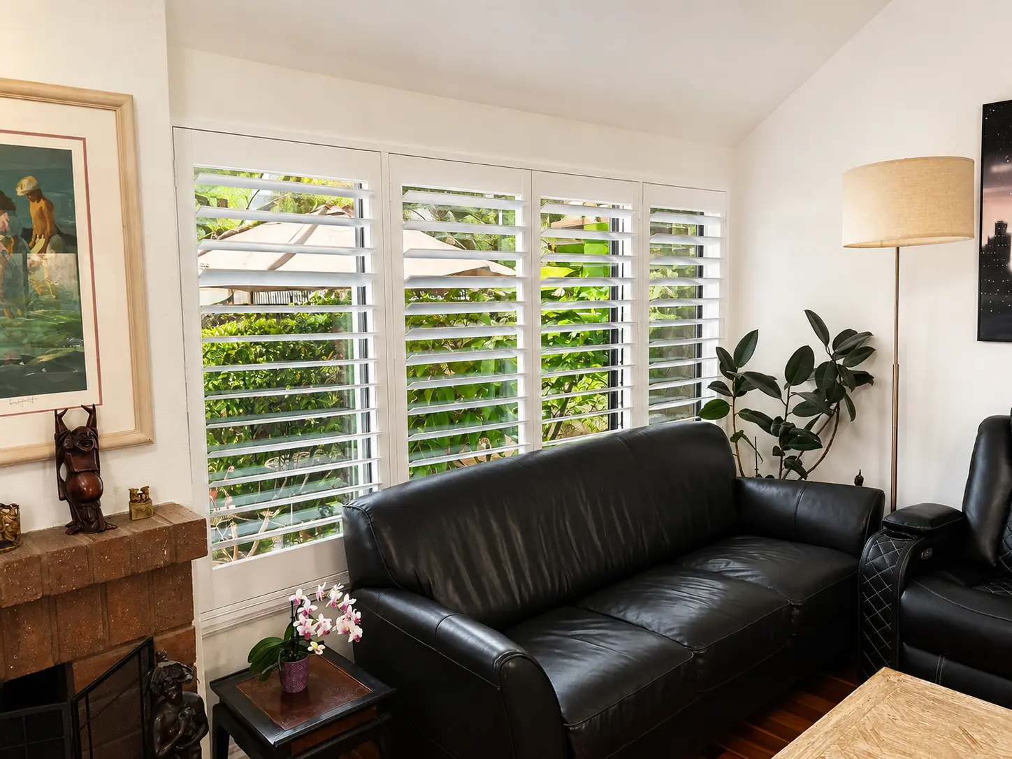 White plantation shutters across four windows in a small living room