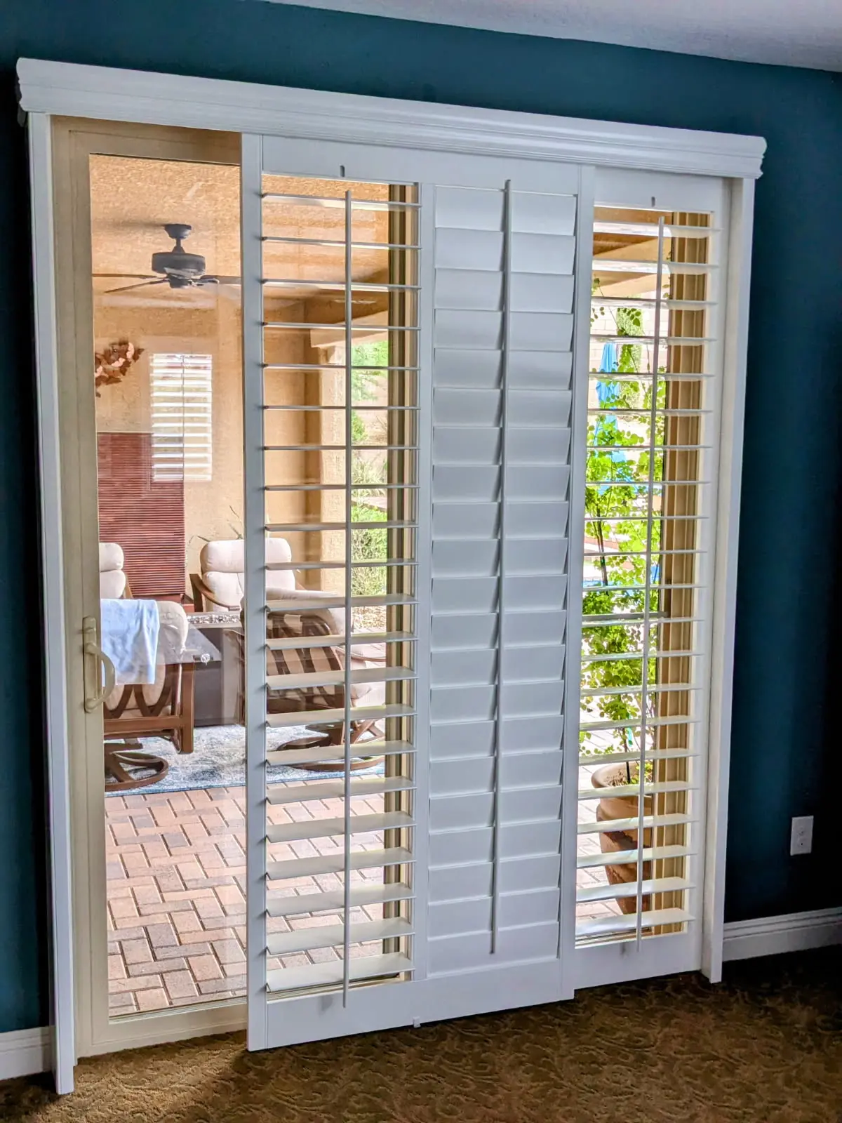 White bypass-track plantation shutters partially closed on a patio slider