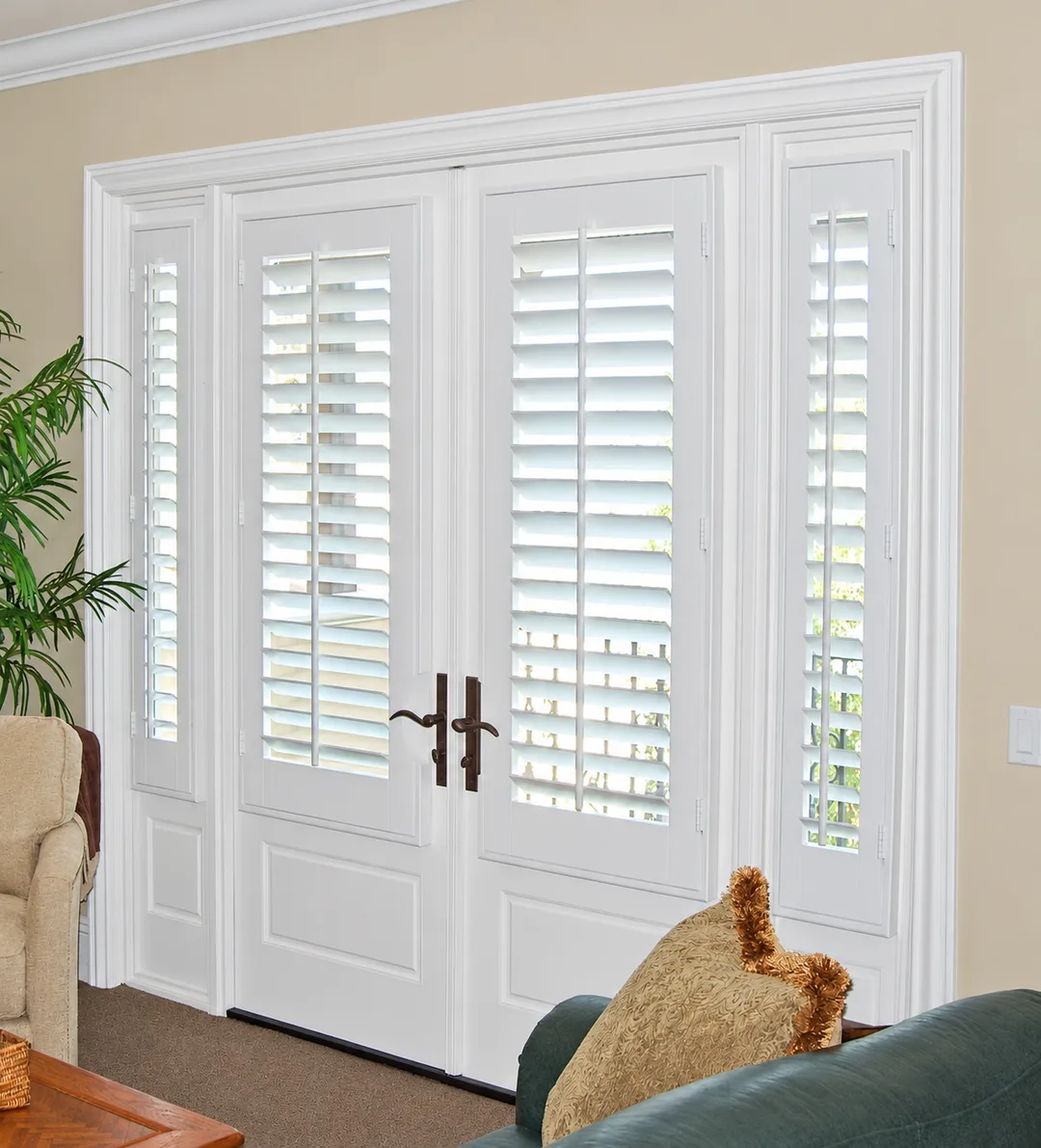 White plantation shutters on a pair of French doors and matching sidelights, with handle cutouts around the door hardware