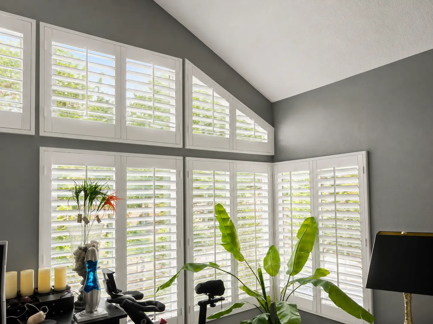 White plantation shutters on tall and angled-top windows in a vaulted room