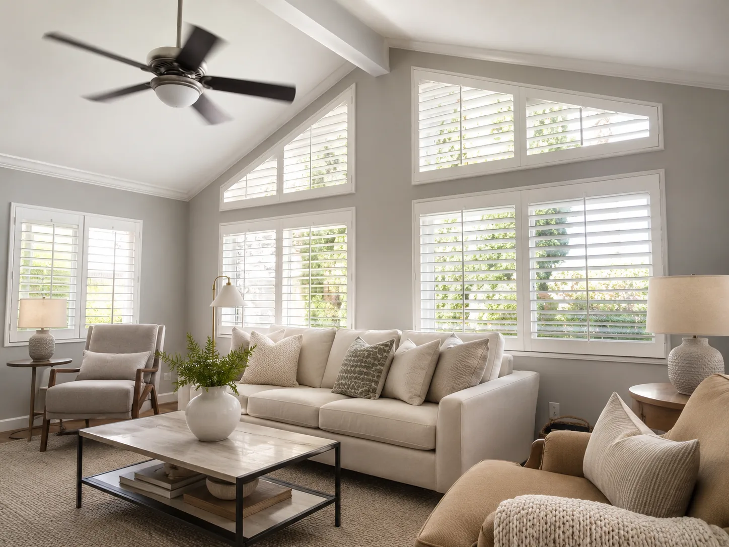 White angled-top specialty plantation shutters on clerestory windows under a vaulted living room ceiling