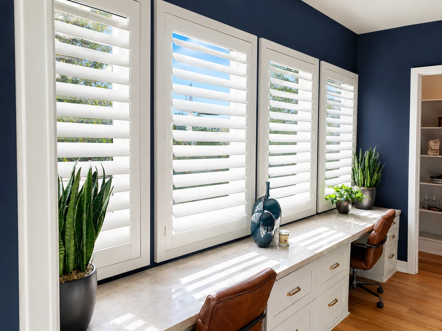 White Polylux plantation shutters on tall windows in a navy-walled home office with twin built-in desks