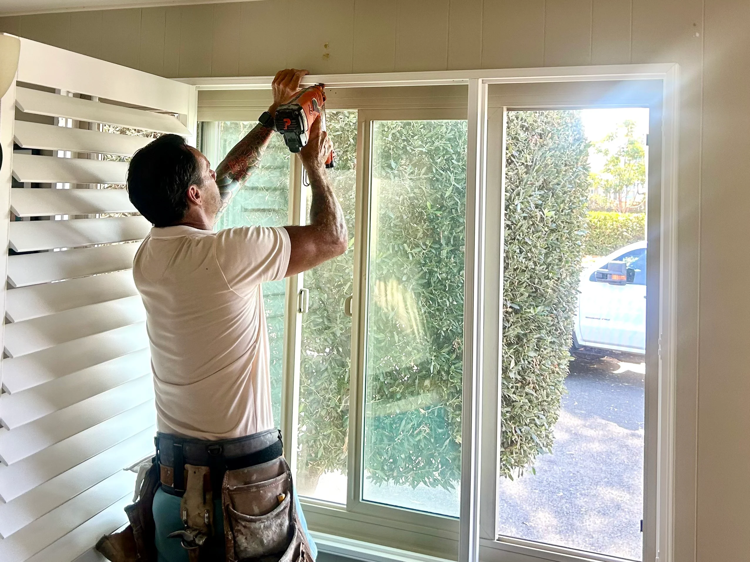 Golden West installer mounting plantation shutters on a sliding door