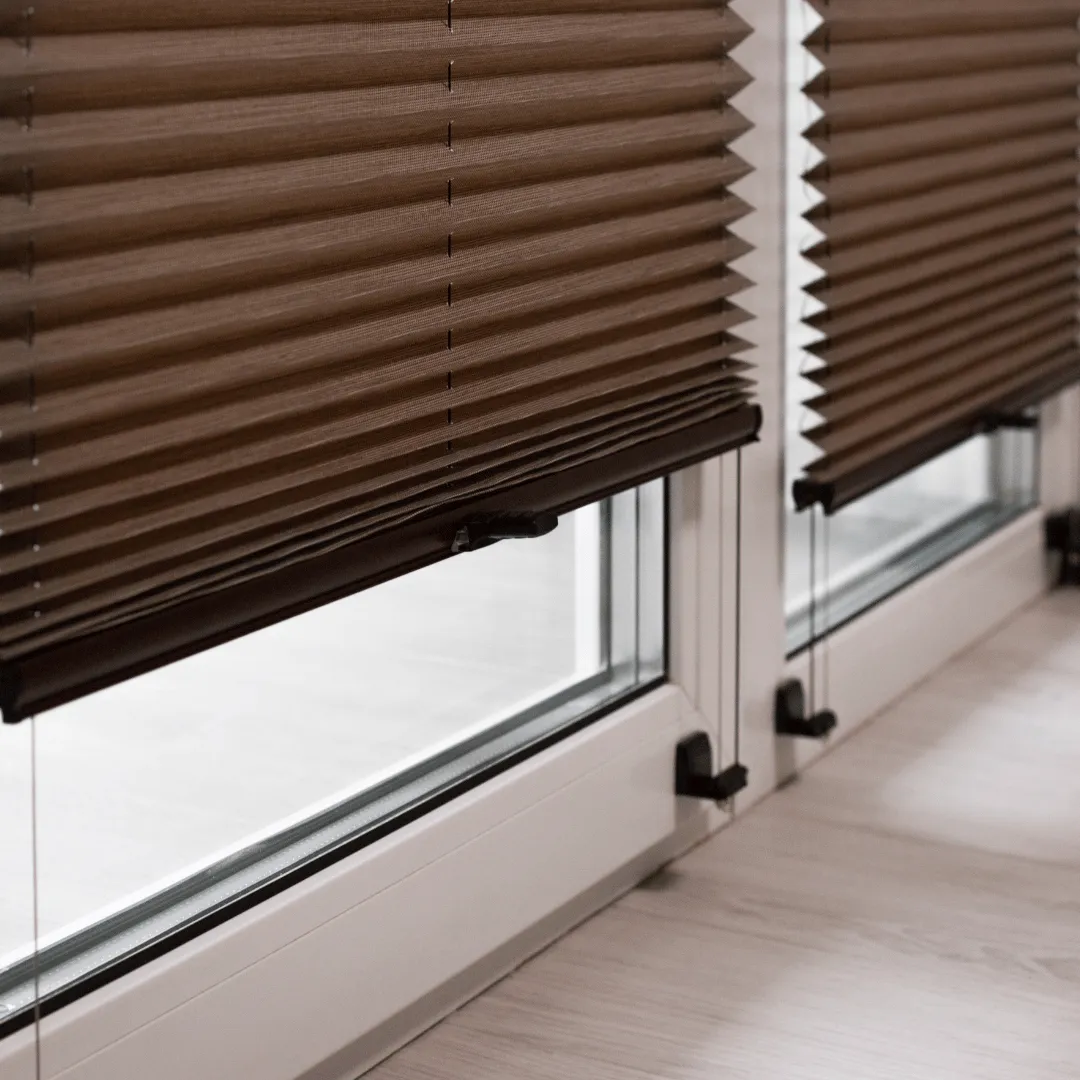 Brown pleated shades partially raised over sliding glass doors