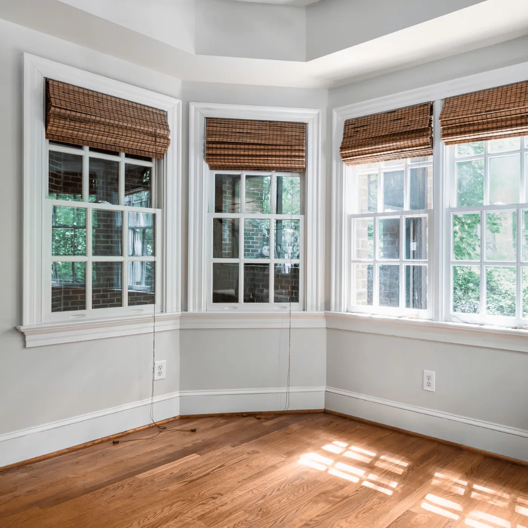 Natural bamboo woven wood shades on bay windows in a sunlit room