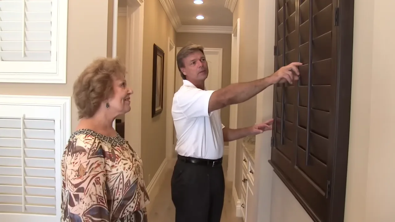 Golden West owner John showing a dark wood plantation shutter to a client in her home